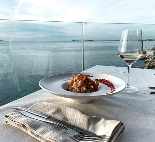 a plate of food on a table with a glass of wine at Hotel Nimfa in Vlorë