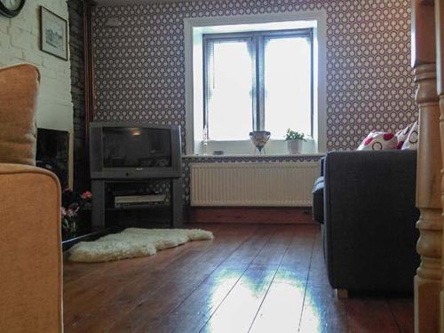 a living room with a television and a window at 12 Rattle Row in Holmfirth