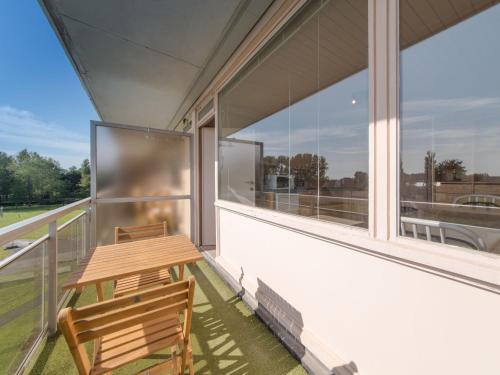 a balcony with a wooden table and a bench at Apartment Empaja great views and parking by Interhome in De Haan