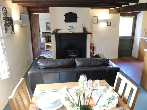uma sala de estar com um sofá de couro preto e uma mesa em South Sandpark Cottage em Barnstaple