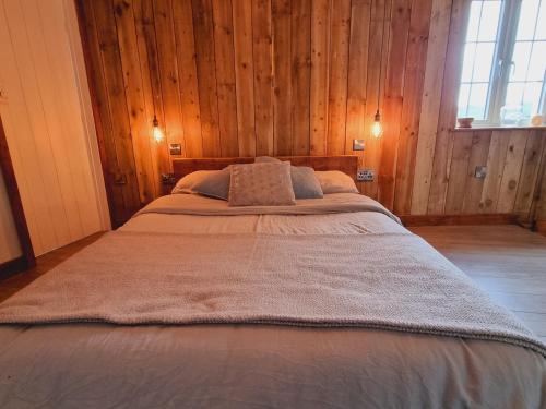 Cama grande en habitación con paredes de madera en Pass the Keys Charming 19th century country cottage for 2 guests, en Exeter