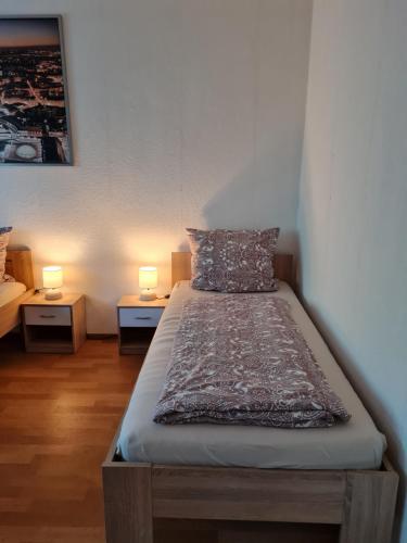 a bed in a room with two lamps on tables at Monteurwohnung Mockau in Leipzig