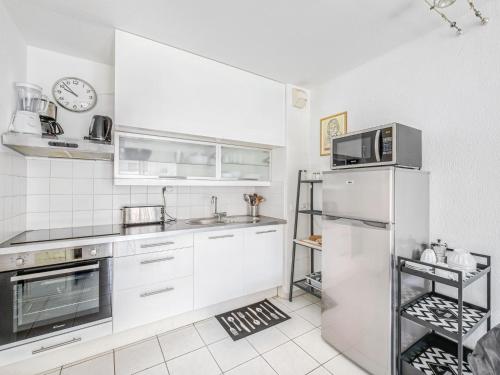 a kitchen with white cabinets and a refrigerator at Apartment Le Cesarée-5 by Interhome in Fréjus