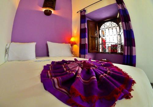 una camera con un letto bianco e una parete viola di Dar Narjis a Marrakech