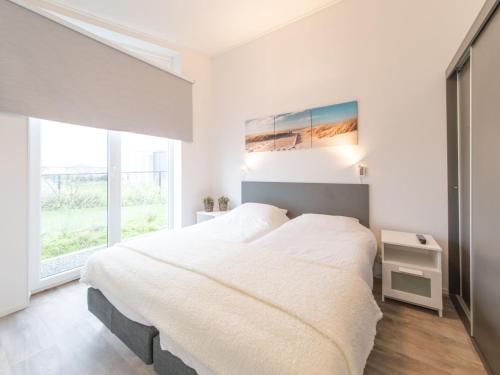 a white bedroom with a large bed and a window at Holiday Home Ruisweg 38 by Interhome in Wemeldinge
