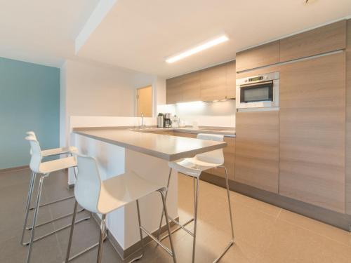 eine Küche mit einer weißen Theke und weißen Stühlen in der Unterkunft Apartment Residentie Odyssea I by Interhome in Bredene