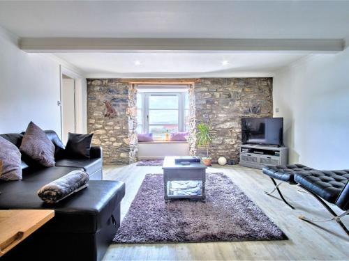 sala de estar con sofá negro y pared de piedra en Apartment Imperial Apartment by Interhome, en Oban