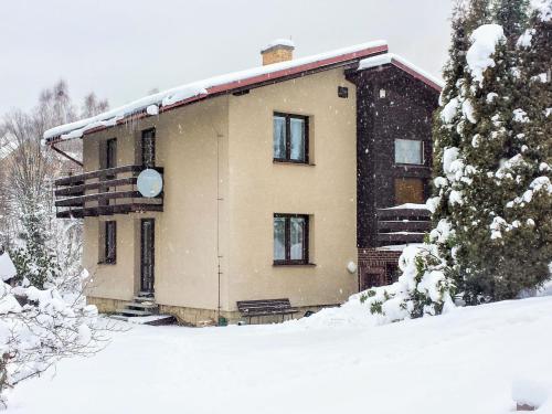 a house covered in snow in front of a tree at Holiday Home Desná v Jizerských horách by Interhome in Desná