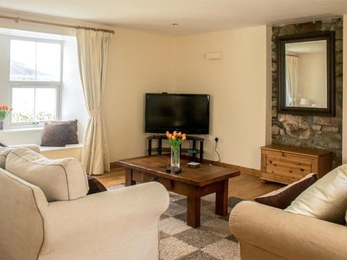 a living room with a television and a table with flowers on it at Holiday Home Old School by Interhome in Dunan