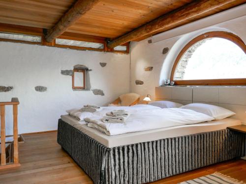 een slaapkamer met een groot bed en een gewelfd raam bij Holiday Home Scateto 66 by Interhome in Malvaglia