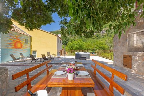 un patio con bancos de madera y una mesa con flores en Holiday Home Ana's Paradise, en Mlini