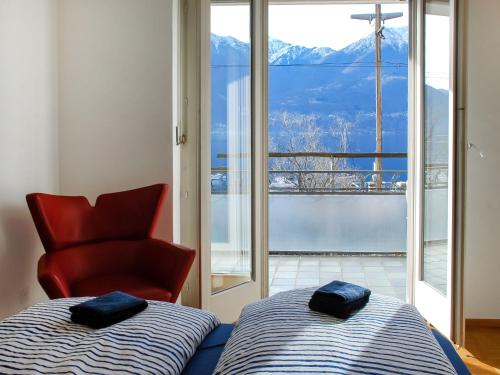 a bedroom with a bed and a red chair at Apartment San Quirico by Interhome in Minusio