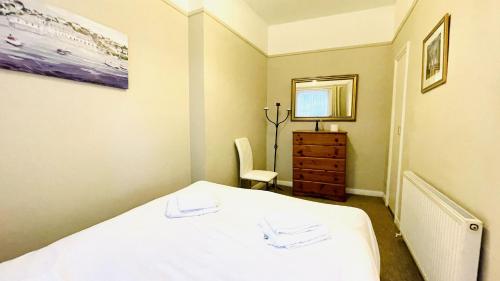 a bedroom with a white bed and a dresser in it at 2 Dartview - Close to the Water, River Views, Ground Floor Access in Dartmouth