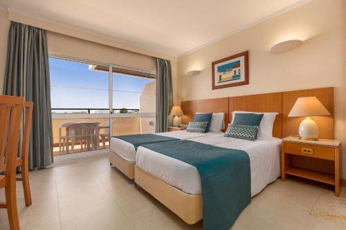 a hotel room with a bed and a balcony at Interpass Vau Hotel Apartamentos in Portimão