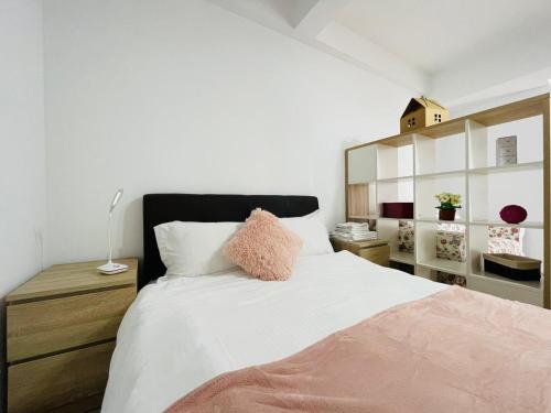 - une chambre avec un lit doté de draps blancs et d'oreillers roses dans l'établissement Xclusive apartment, à Iaşi