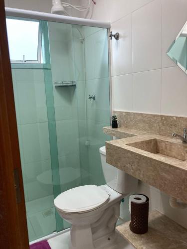 een badkamer met een toilet en een glazen douche bij Pé na areia Fábio e Silvia in Praia Grande