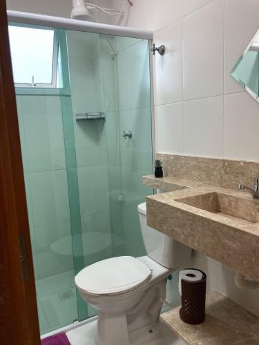 a bathroom with a toilet and a glass shower at Pé na areia Fábio e Silvia in Praia Grande