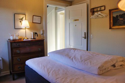 a bedroom with a bed and a dresser and a window at Schackenborg Slotskro in Tønder