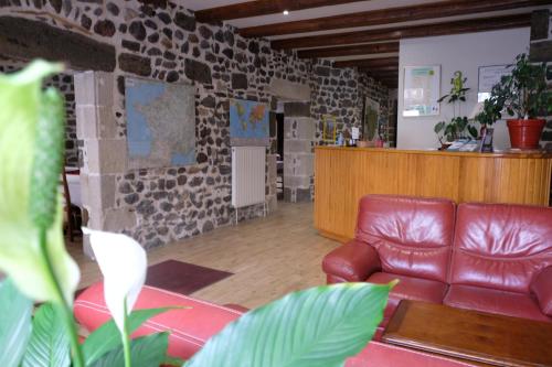 a living room with a leather couch and a stone wall at Le Bilboquet in Le Puy en Velay