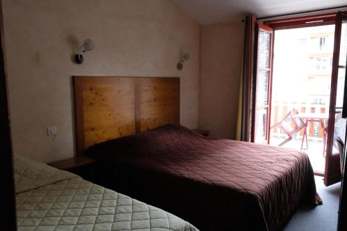 a bedroom with two beds and a large window at Le Bilboquet in Le Puy en Velay