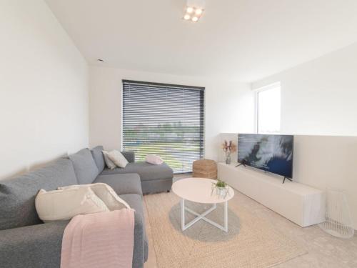 a living room with a gray couch and a table at Holiday Home Bredunepark-2 by Interhome in Bredene