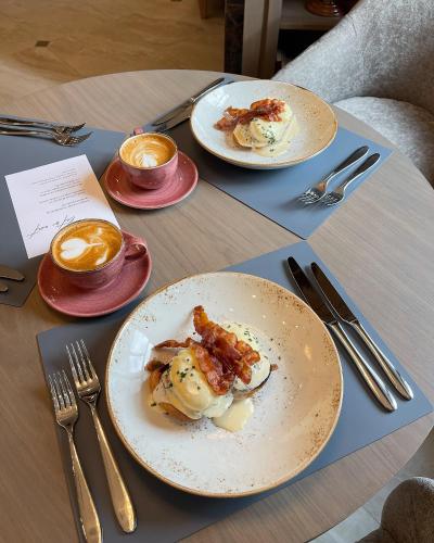 a table with plates of food and cups of coffee at CALVARY Hotel & Restaurant Vilnius in Vilnius