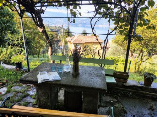 a bench with a table with a book and a bottle at Holiday Home Giò by Interhome in Perledo