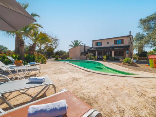a pool with chairs and an umbrella in front of a house at Holiday Home Es Rafalet by Interhome in Llucmajor