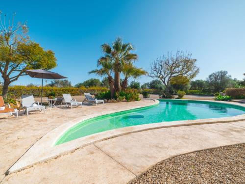 a swimming pool with chairs and an umbrella at Holiday Home Es Rafalet by Interhome in Llucmajor