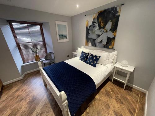 Schlafzimmer mit einem blauen und weißen Bett und einem Fenster in der Unterkunft Lower Flat, Nicolson House. in Portree