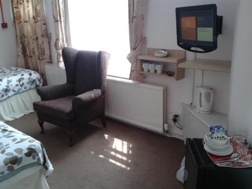 a bedroom with a chair and a tv and a bed at Overnight Stays Stockport in Stockport