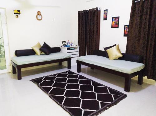 a living room with two couches and a rug at Aarudhara Holiday Home (A Home away from Home) in Puducherry