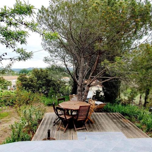 una mesa y sillas en una terraza de madera en Villa Vincent, en Aramon