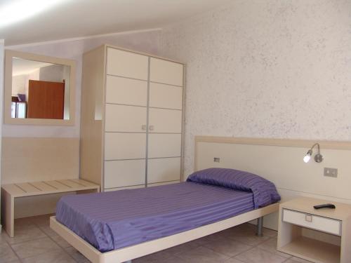 B&B Il Girasole في Rogliano: غرفة نوم مع سرير أرجواني وخزانة