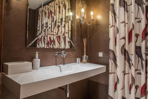baño con lavabo blanco y cortina de ducha en Casa Rural Los Tres Lugares, en San Martín de Trevejo