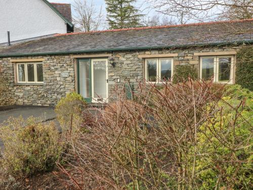 a stone house with windows and bushes in front of it at Apple Tree Cottage in Windermere