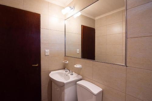 a bathroom with a sink and a toilet and a mirror at Fitz Roy Hostería de Montaña - El Chaltén in El Chalten