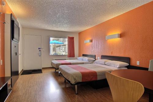 2 Betten in einem Zimmer mit orangefarbenen Wänden in der Unterkunft Motel 6-Albuquerque, NM - Coors Road in Albuquerque