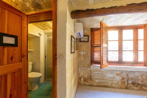 uma casa de banho com um WC e uma janela em Ta Rummiena Farmhouse em Xewkija