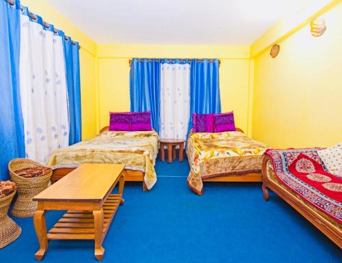 a room with three beds and a table in it at Dew Drop Homestay in Kalimpong