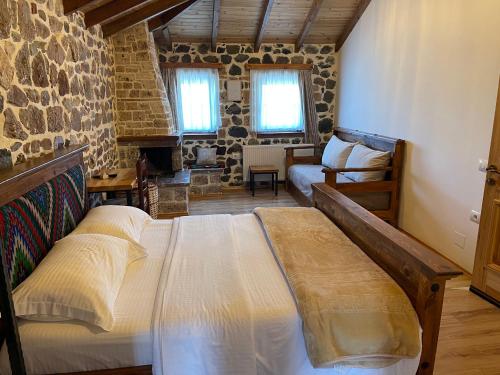 a bedroom with a bed and a stone wall at Bujtina Liana Voskopoje in Voskopojë