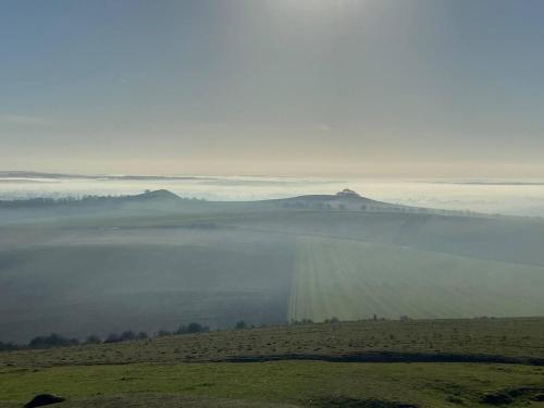 a foggy field with a view of a lake and mountains at Cosy Rural Retreat Sleeps 3 & PetFriendly in Pewsey