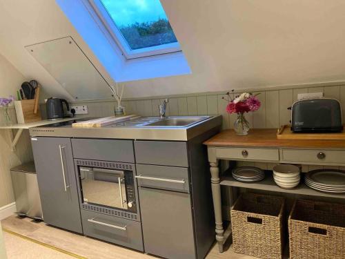 una pequeña cocina con fregadero y barra con platos en Stylish getaway in the heart of the Pewsey Vale en Pewsey
