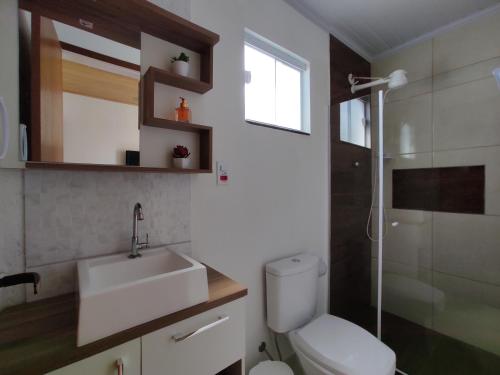 Un baño con inodoro, lavabo y ducha. en Casa 200 Arraial, en Arraial do Cabo