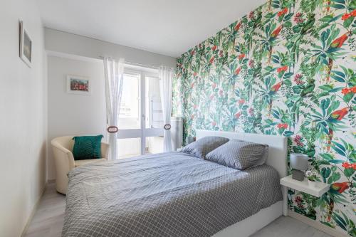 une chambre avec un lit avec un papier peint fleuri dans l'établissement Magnifique vue sur l'océan- Appartement pour 2, à Plage-des-Demoiselles