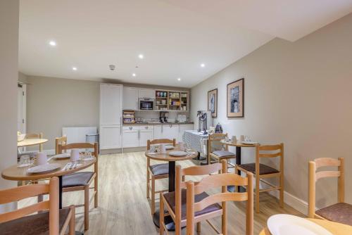a restaurant with wooden tables and chairs and a kitchen at Goswell House Hotel central Windsor in Windsor
