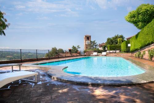 a large swimming pool with a bench in front of a building at Hotel Castello di Santa Vittoria in Santa Vittoria dʼAlba