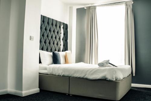 a bedroom with a bed with a headboard and a window at Dealhouse Apartments 10 in Huddersfield