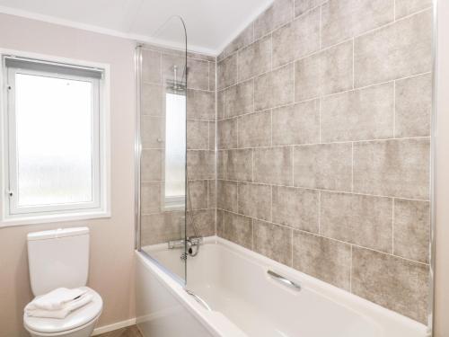 a bathroom with a tub and a toilet and a window at Fairways 4 - Sunny Meadows in Burnham on Sea