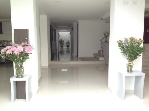 two vases of flowers on tables in a hallway at Hotel Burana in Bogotá